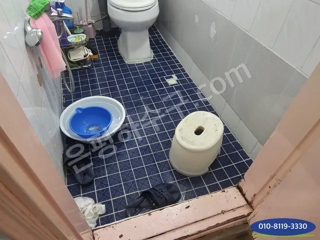 대야와 의자가 놓인 좁은 타일 화장실 바닥